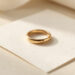 Bague en or éthique posée sur un certificat de traçabilité vierge, éclairée par une douce lumière naturelle dans un style éditorial haut de gamme.